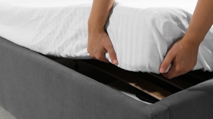Close-up of hands picking up mattress.