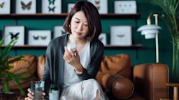 Woman reads medicine bottle label on couch at home.
AsiaVision/E+ via Getty Images
