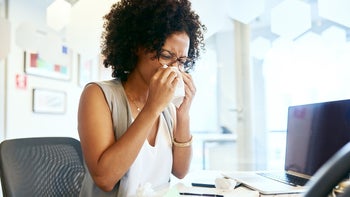diphenhydramine: allergies: sneezing: woman blowing nose at desk 1065221726