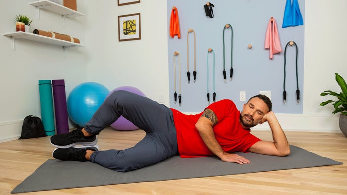 Man doing side lying quad stretch exercise while laying on a yoga mat