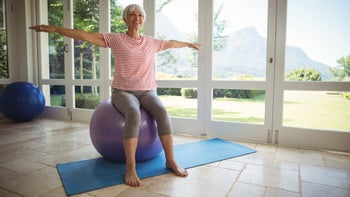 Health: movement exercise: senior woman stretching and balancing on workout ball-645435106