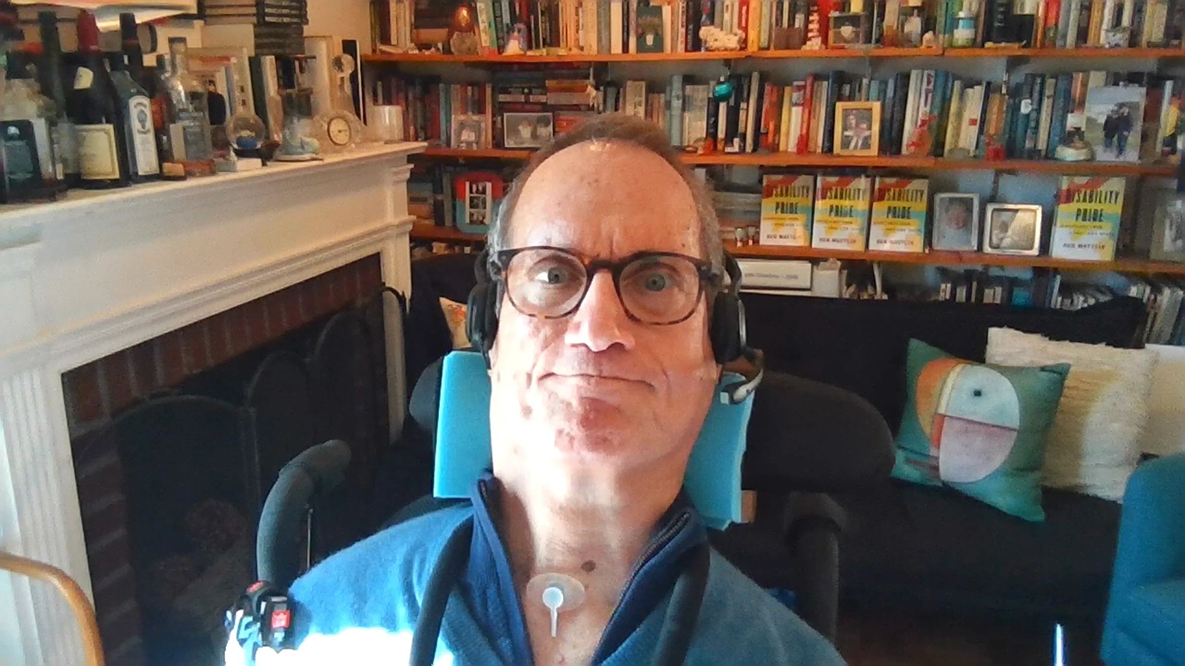 Ben Mattlin is pictured sitting in his wheelchair, surrounded by books and a fireplace.