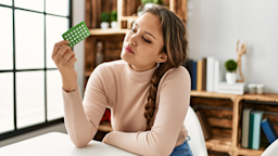 A person holding a blister pack of birth control and thinking.
AaronAmat/iStock via Getty Images Plus 
