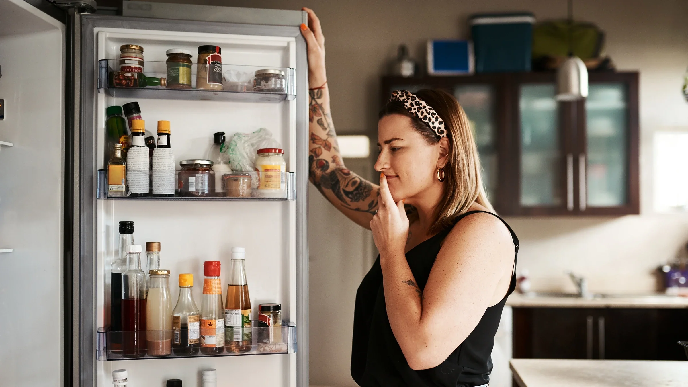 A woman looks inside her refrigerator at home.