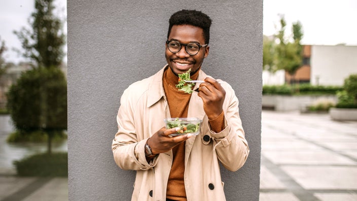 Man eating salad and smiling.