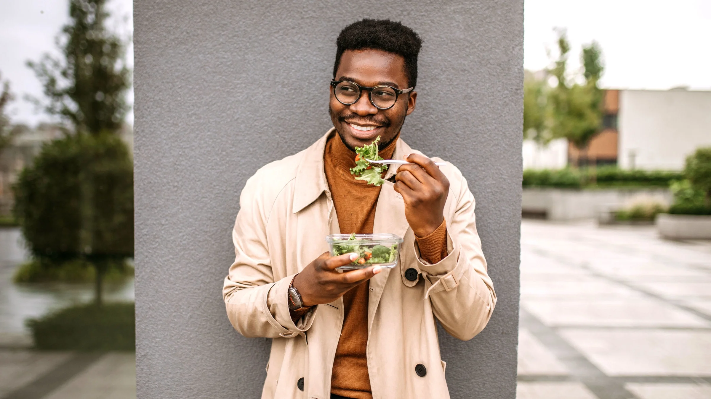 Man eating salad and smiling.