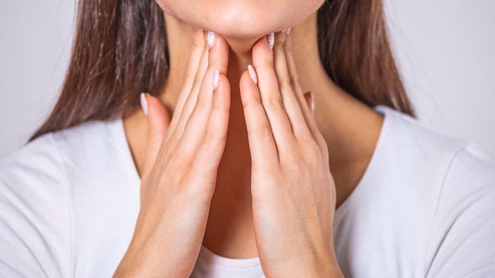 Cropped shot of a person’s neck as they rub their tonsils with their hands.