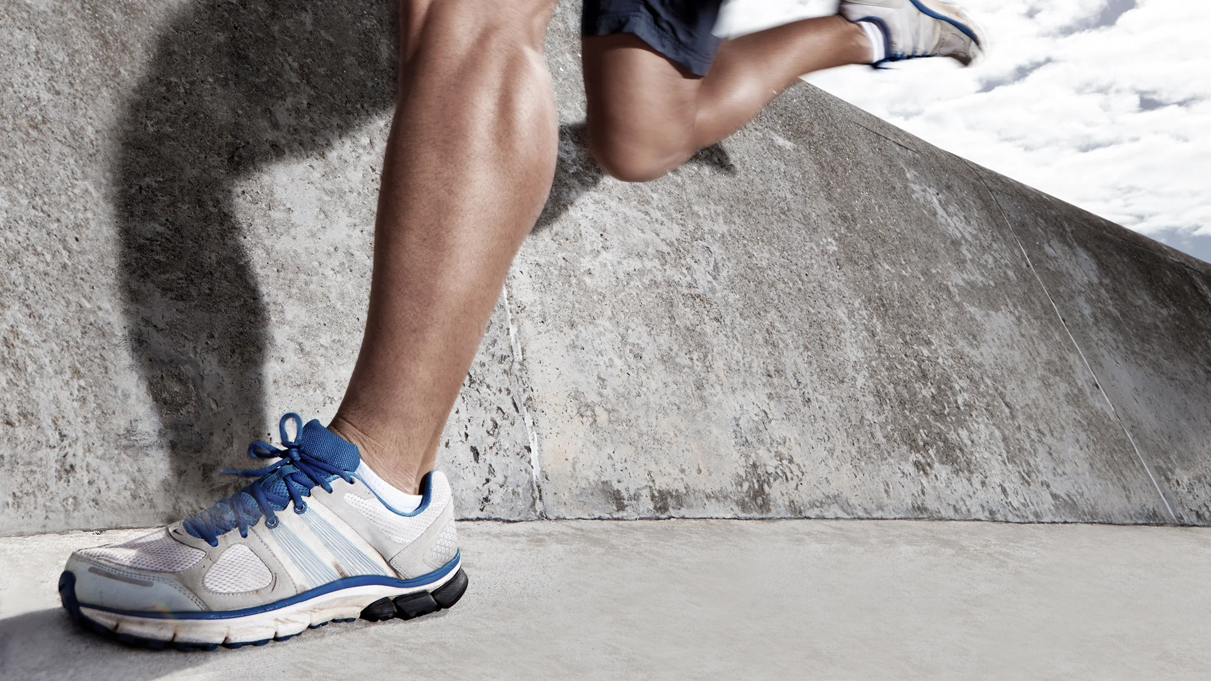 Close-up on a runner's calf muscles mid stride.