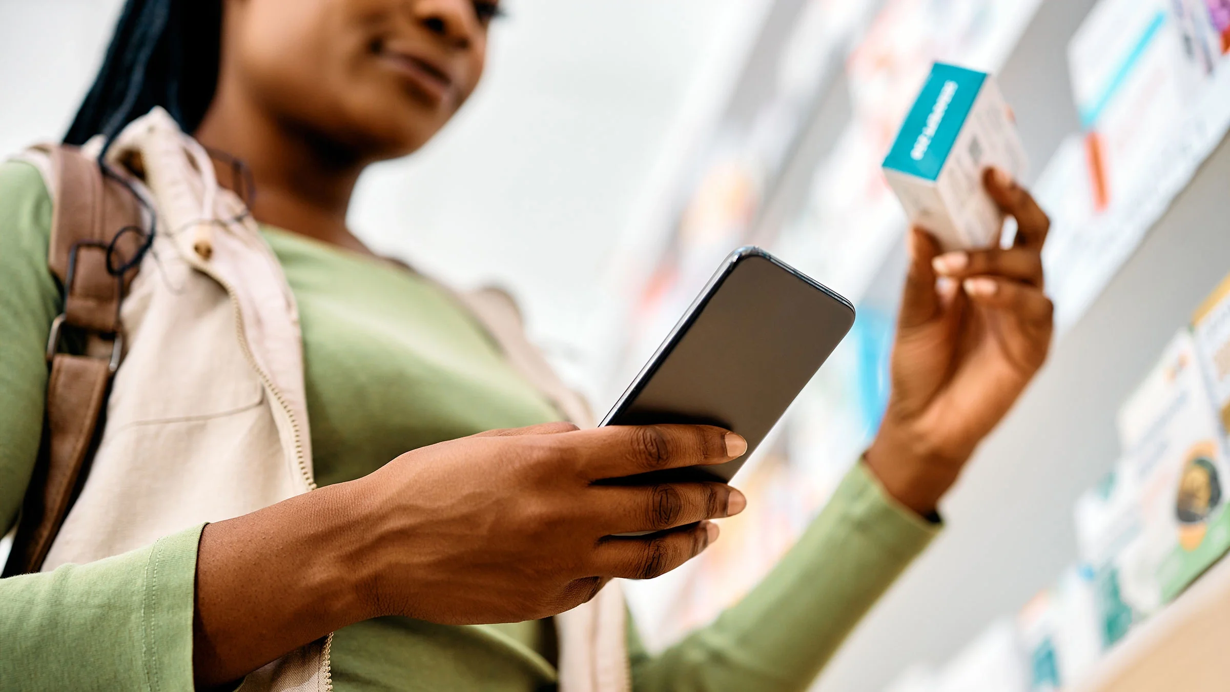 A woman looks at her phone before buying medicine in a pharmacy.
