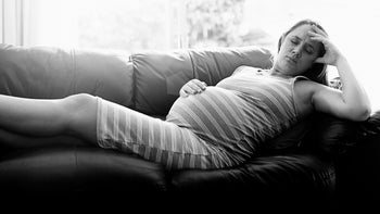 nauseous pregnant woman on couch-672336888