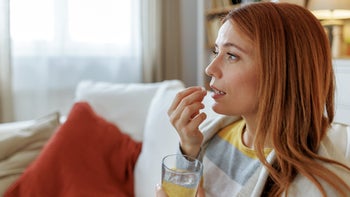 Pharmacy: woman taking medication with water 2196049070