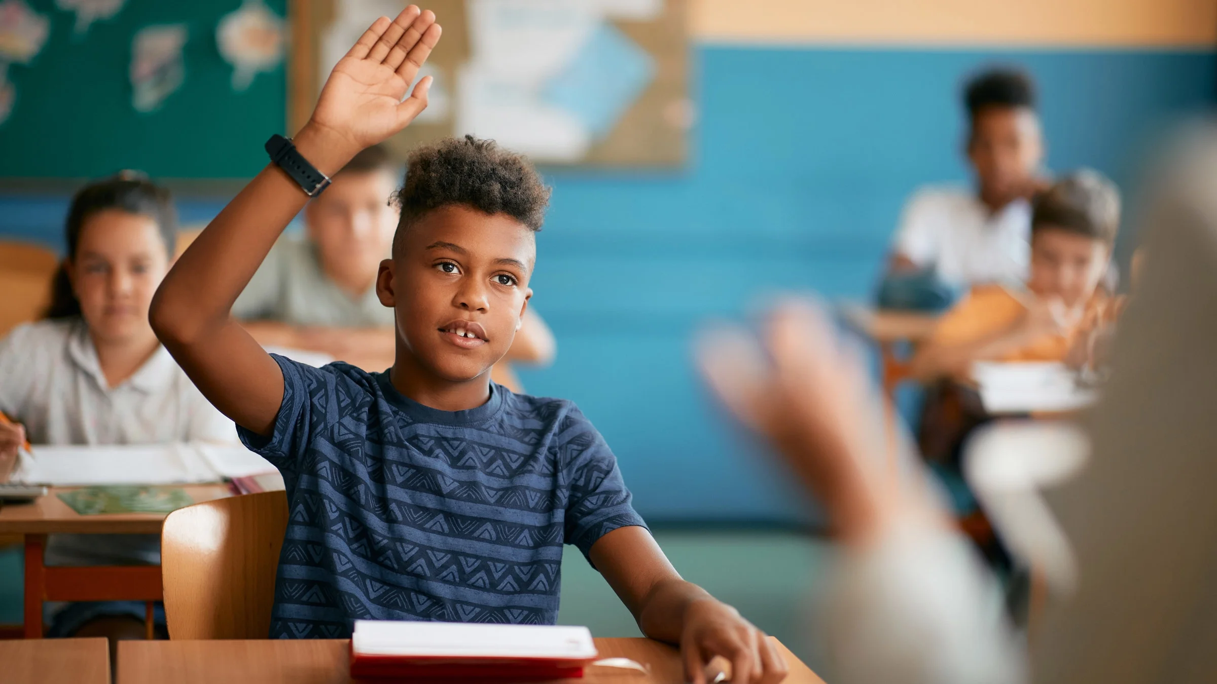 A young student raising their hand in class.