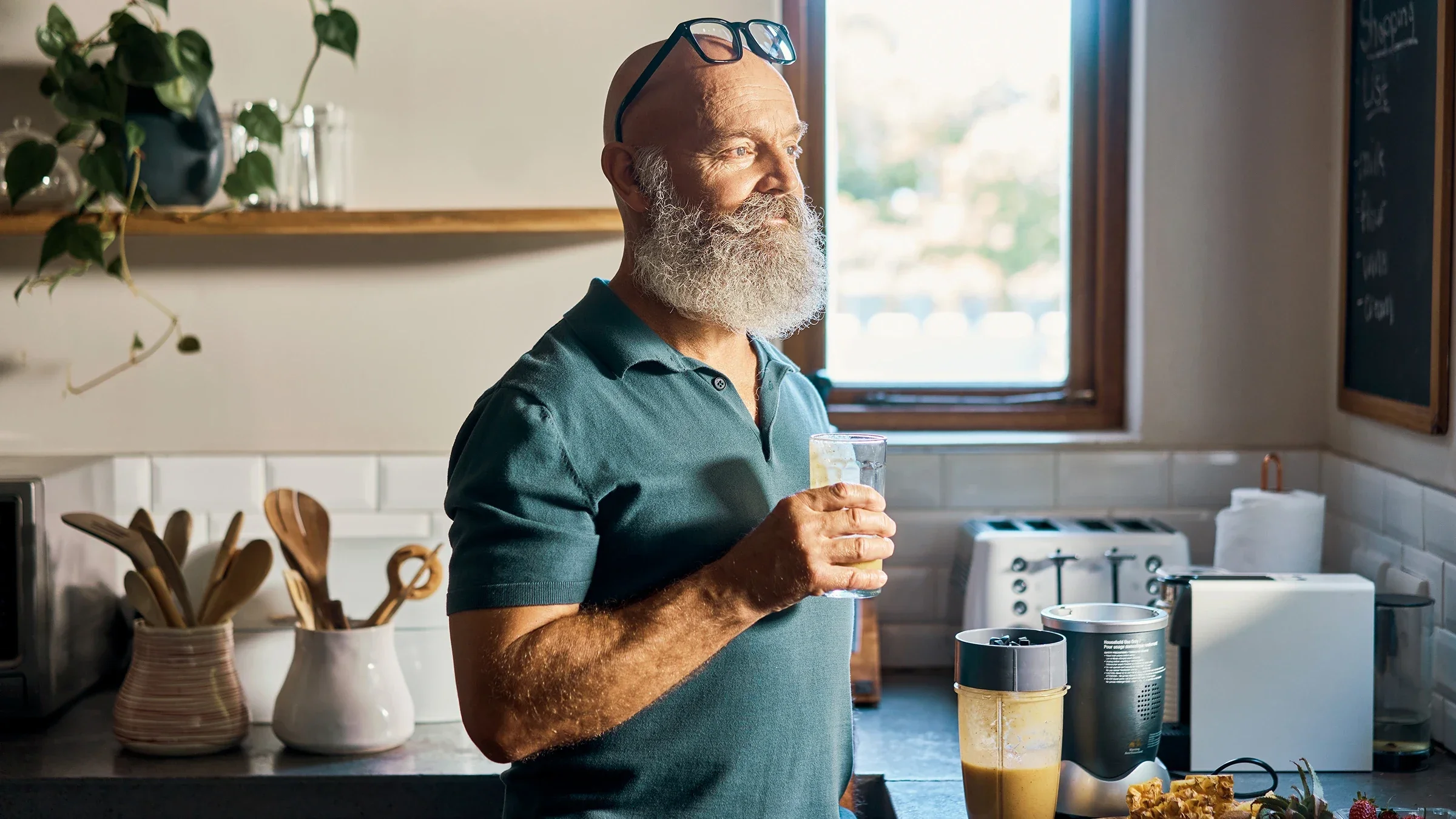 A man drinks a protein shake in his kitchen. 
pixdeluxe/E+ via Getty Images