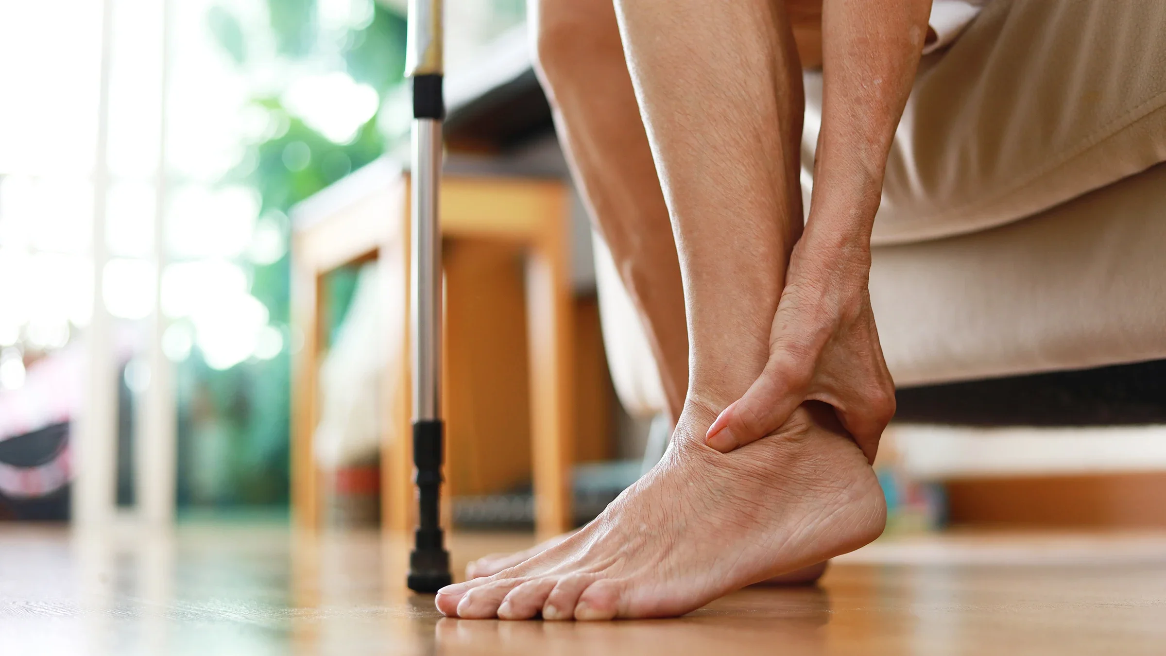 A person bends down to hold the back of their foot.
Thai Liang Lim/E+ via Getty Images