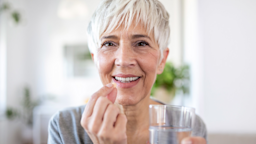 A person holding a pill and a glass of water.
stefanamer/iStock via Getty Images Plus 