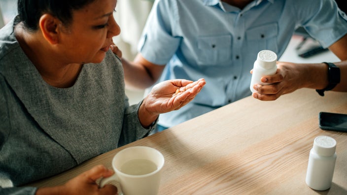 A son helps his mother prepare to take her medication.
