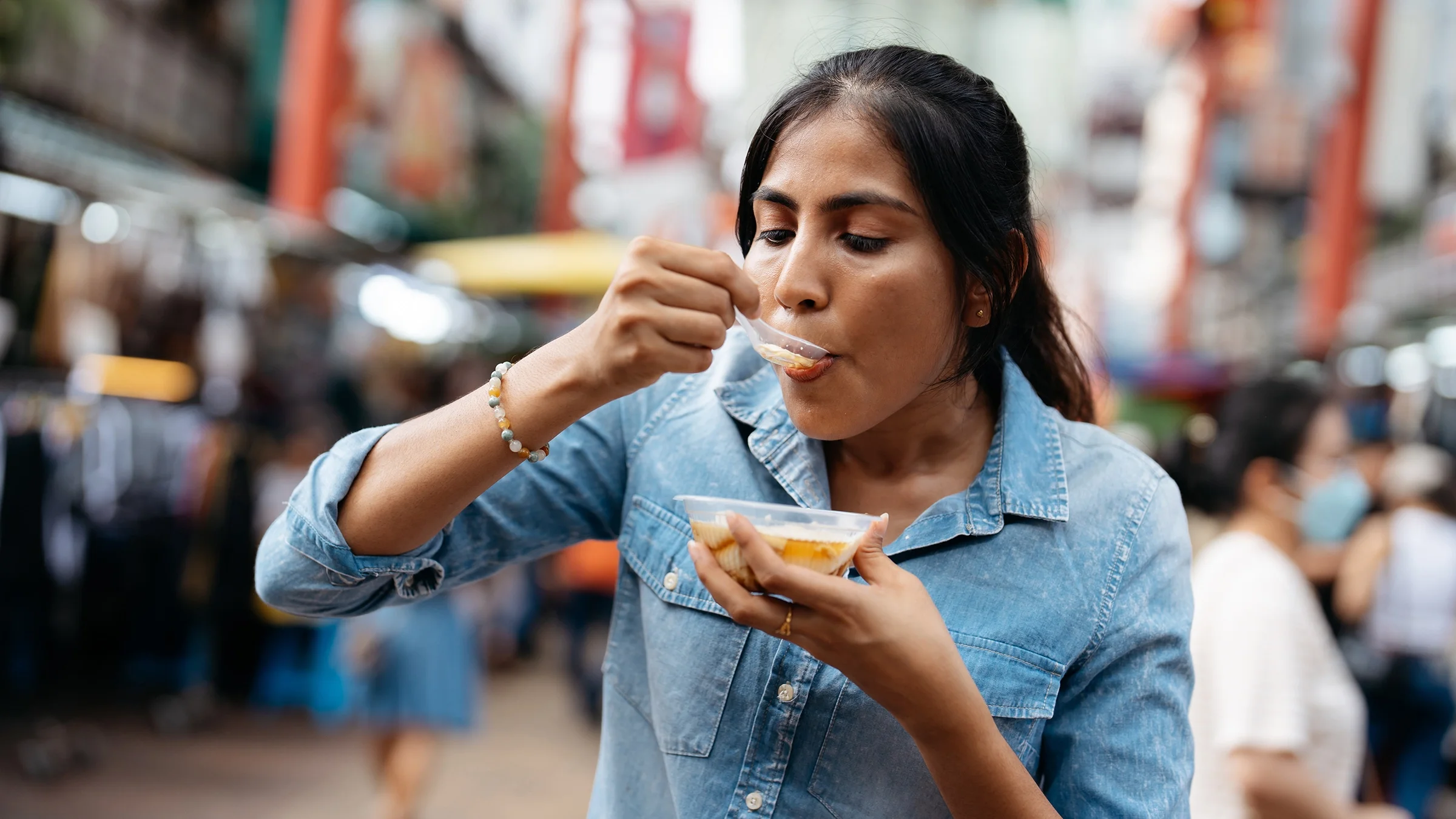 A woman eats with a spoon while walking.