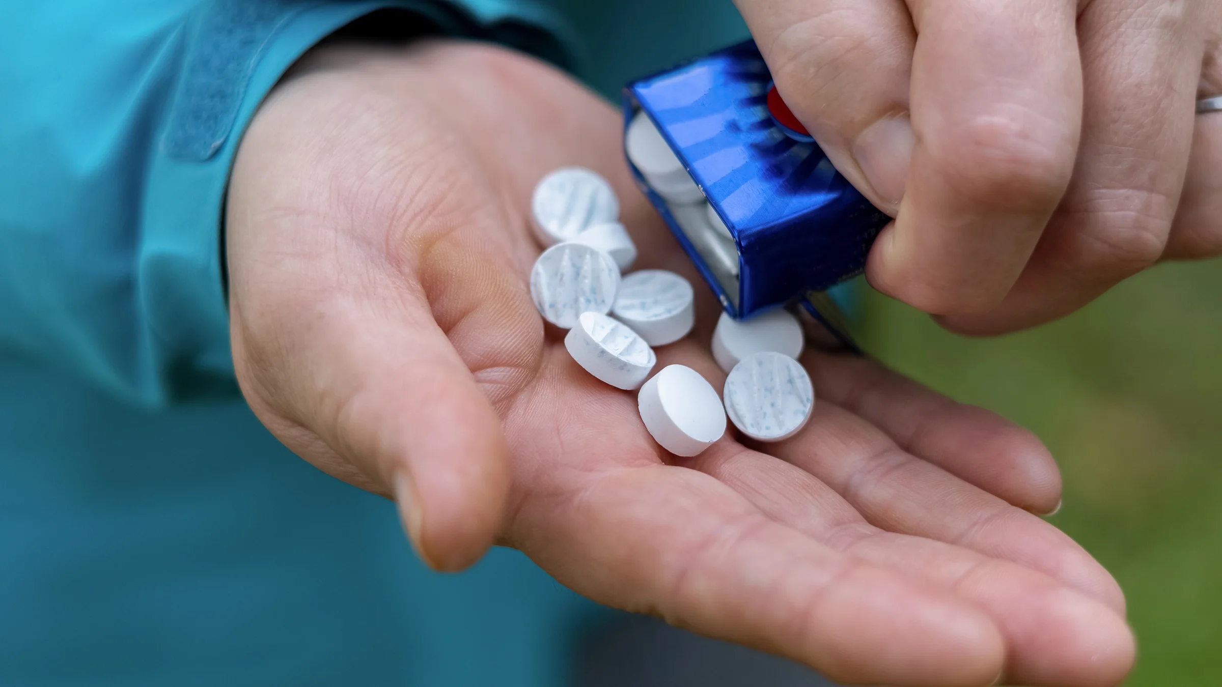 A man pours breath mints into the palm of his hand. 