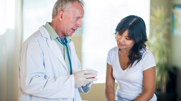 A HCP explaining a pill bottle to an East Asian patient.