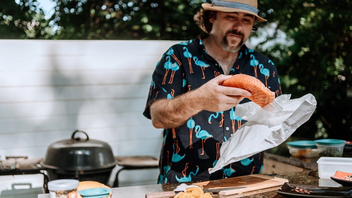 A man prepares raw salmon in his backyard. Salmon is rich in omega-3 fatty acid.