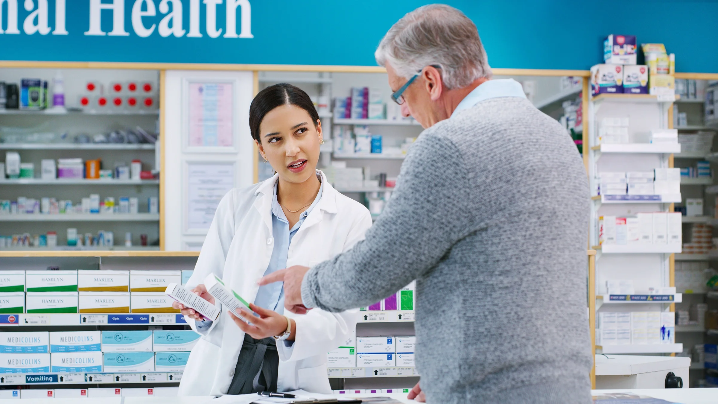 A pharmacist assists a customer in choosing an over-the-counter product. 