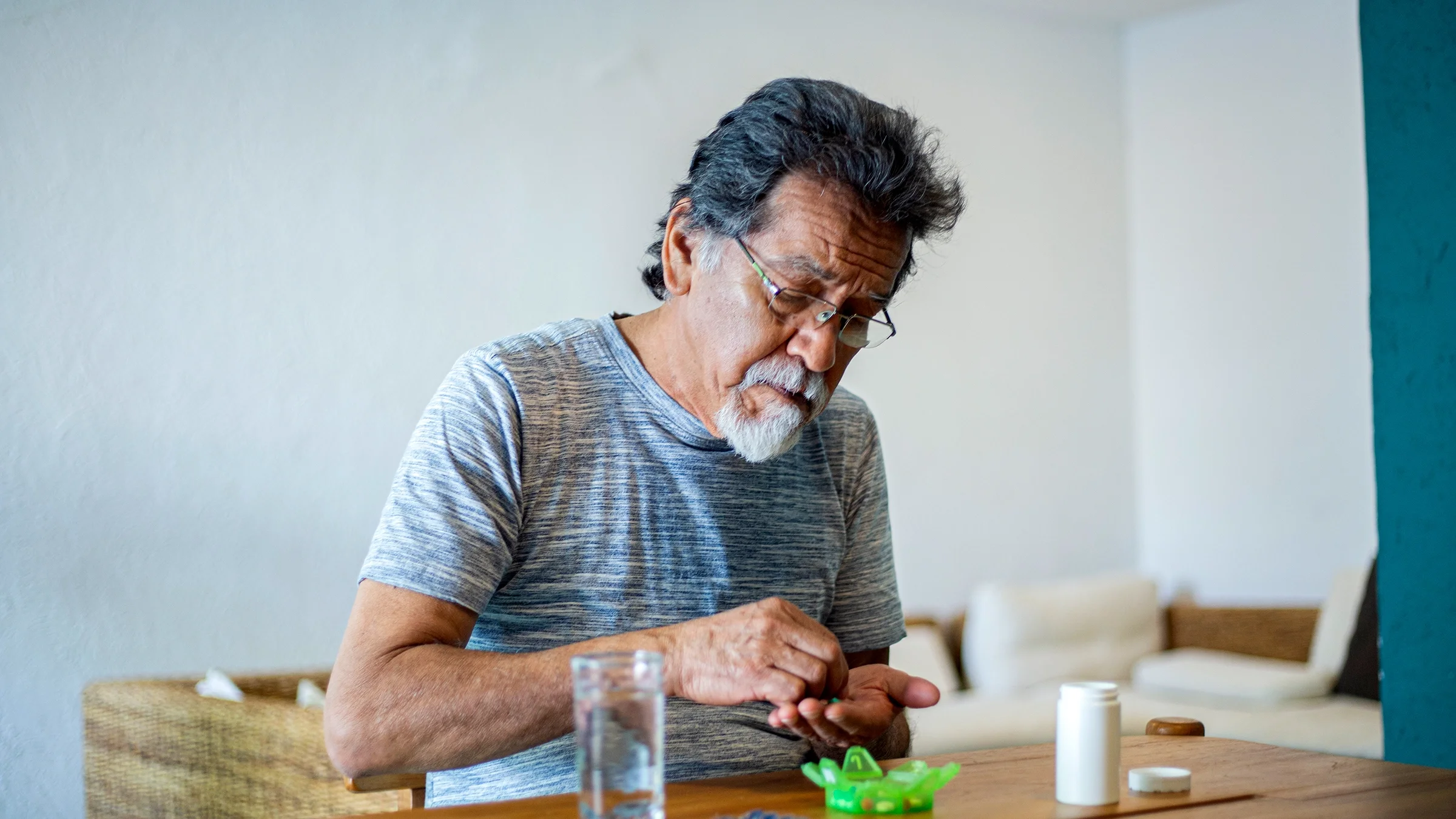 An older man is putting medication into a pill organizer.