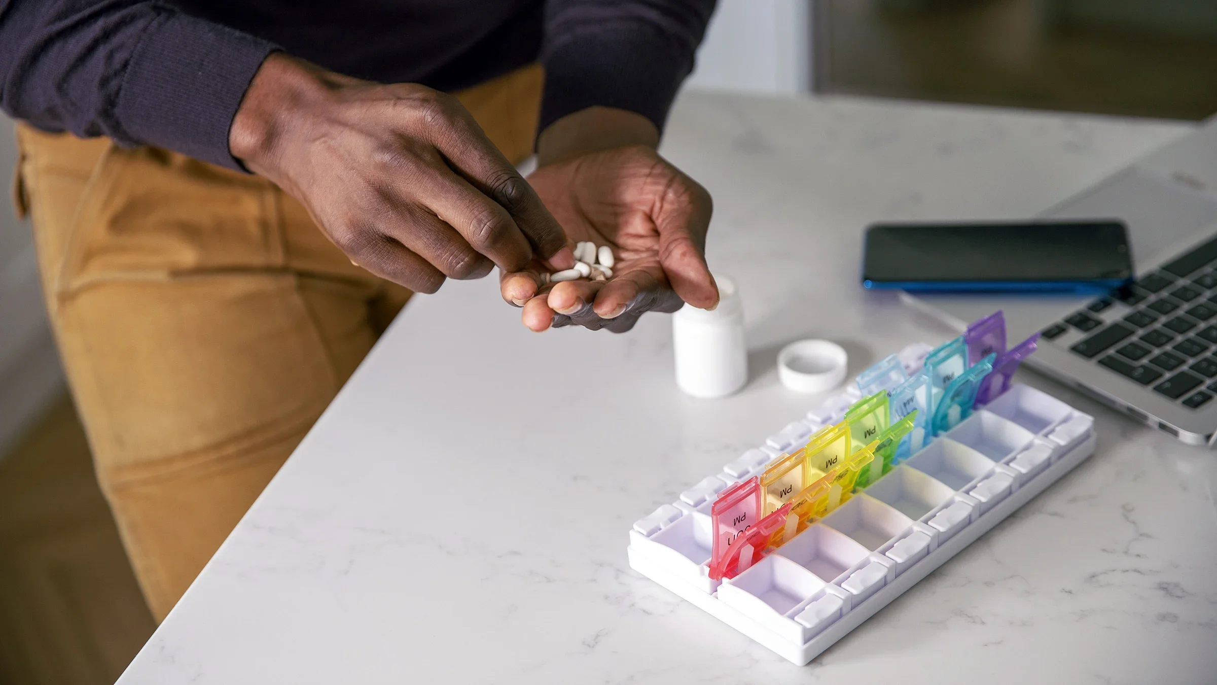 A man places prescription medication in a daily pill organizer.
Fly View Productions/E+ via Getty Images