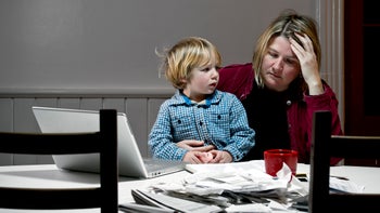 Medical debt: Bankruptcy: mother stressed reviewing finances child on lap-167786996