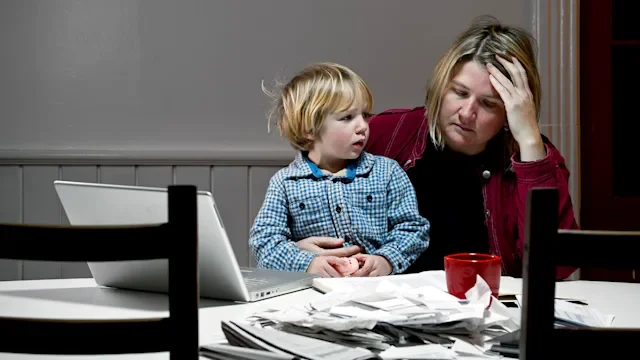 Medical debt: Bankruptcy: mother stressed reviewing finances child on lap-167786996