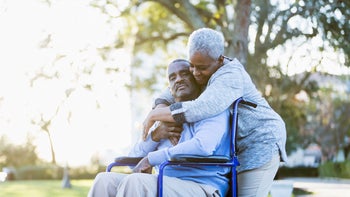 Health: Stroke: senior couple wheelchair hug outdoors 535931641