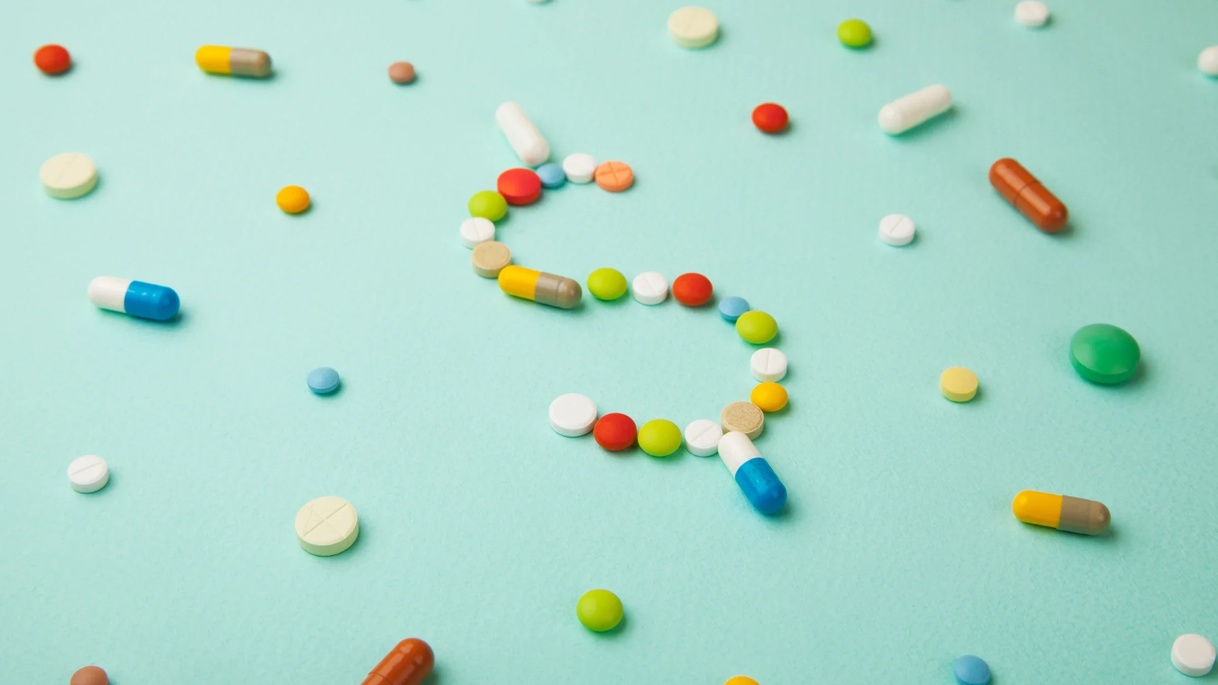 Colorful pills shaping a dollar sign, surrounded by scattered pills, on a light blue background.
ADragan/iStock via Getty Images 