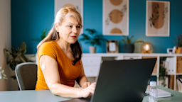A woman with a glucose monitor on her arm uses her laptop.
Pekic/E+ via Getty Images  
