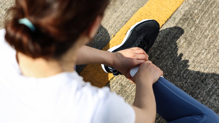 A woman holds her ankle. 