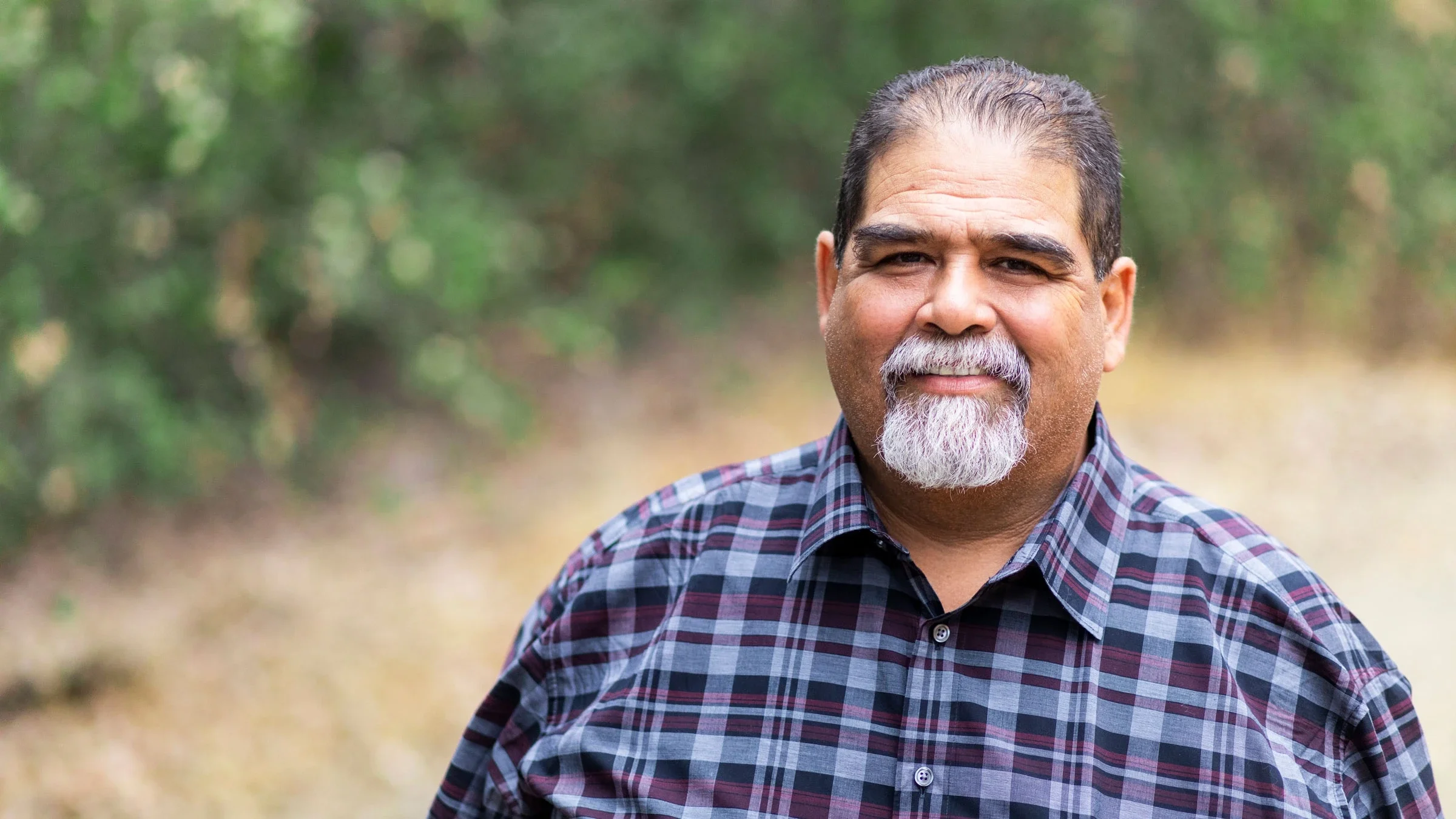 Man in plaid shirt smiling.
