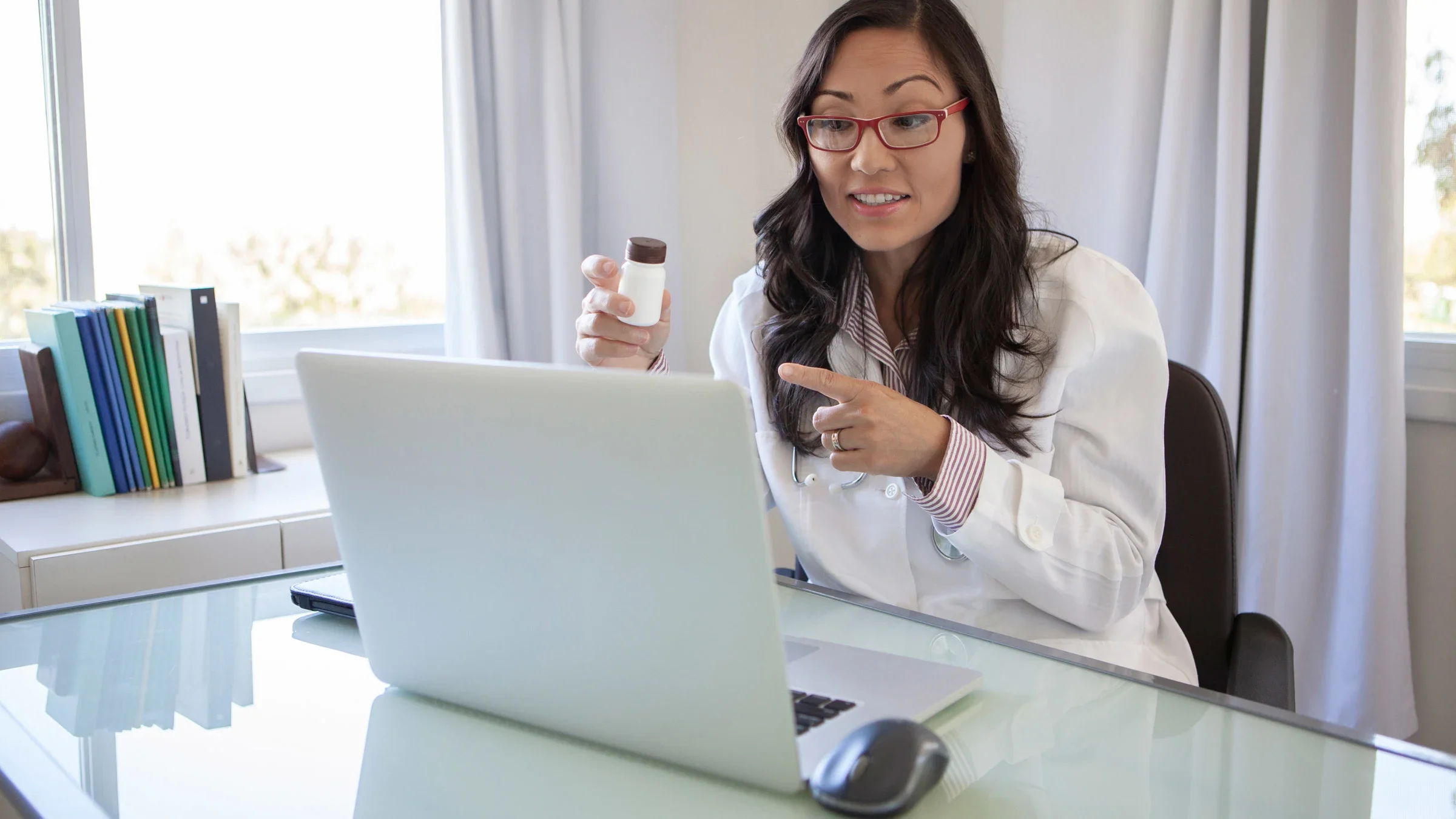 A healthcare provider explaining a pill bottle on a telehealth call.
Renata Angerami/E+ via Getty Images