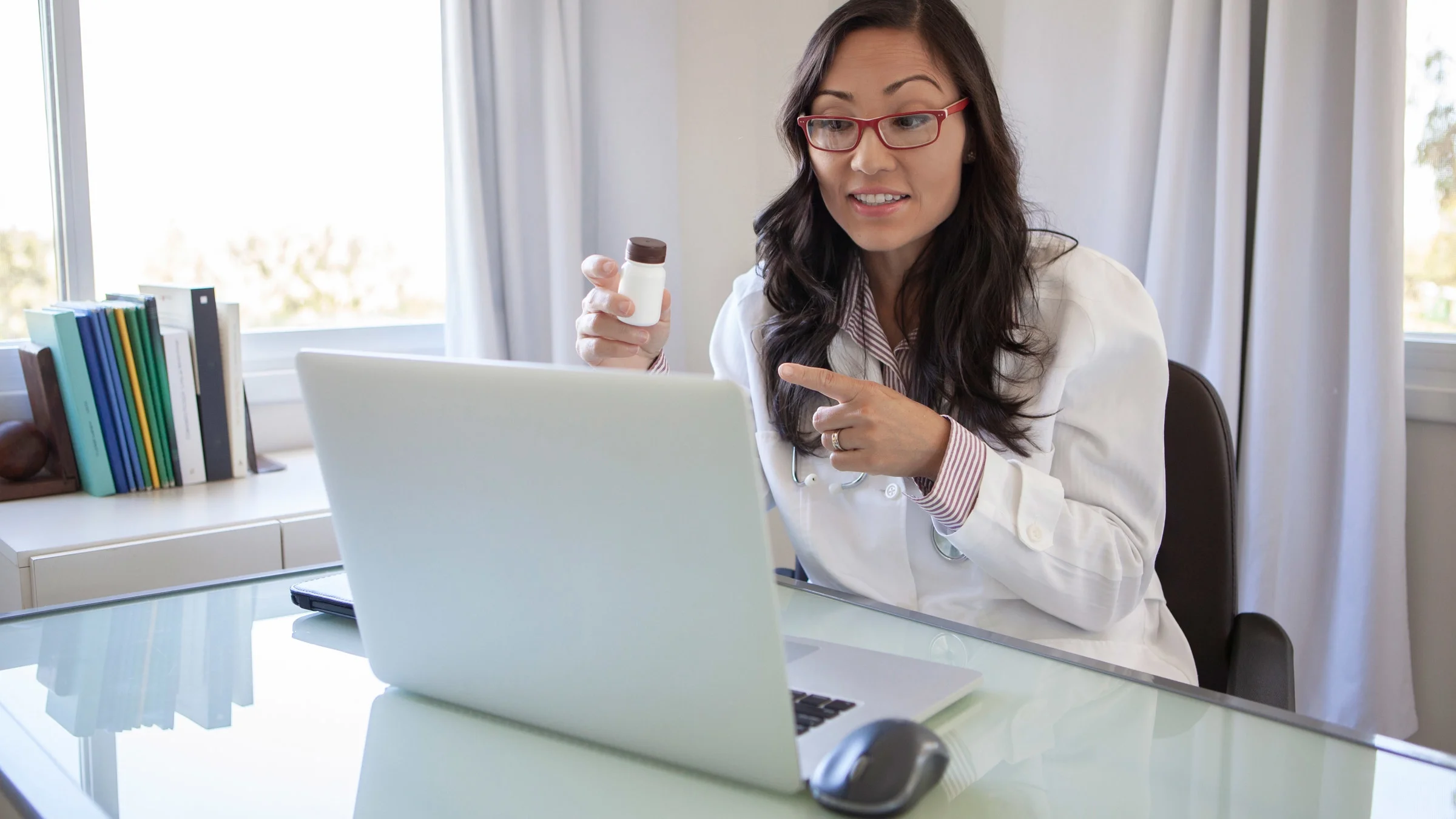 A healthcare provider explaining a pill bottle on a telehealth call.