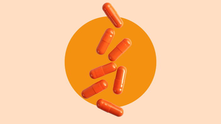 A light orange background with a dark orange circle in the center highlights orange capsule pills falling into frame. 