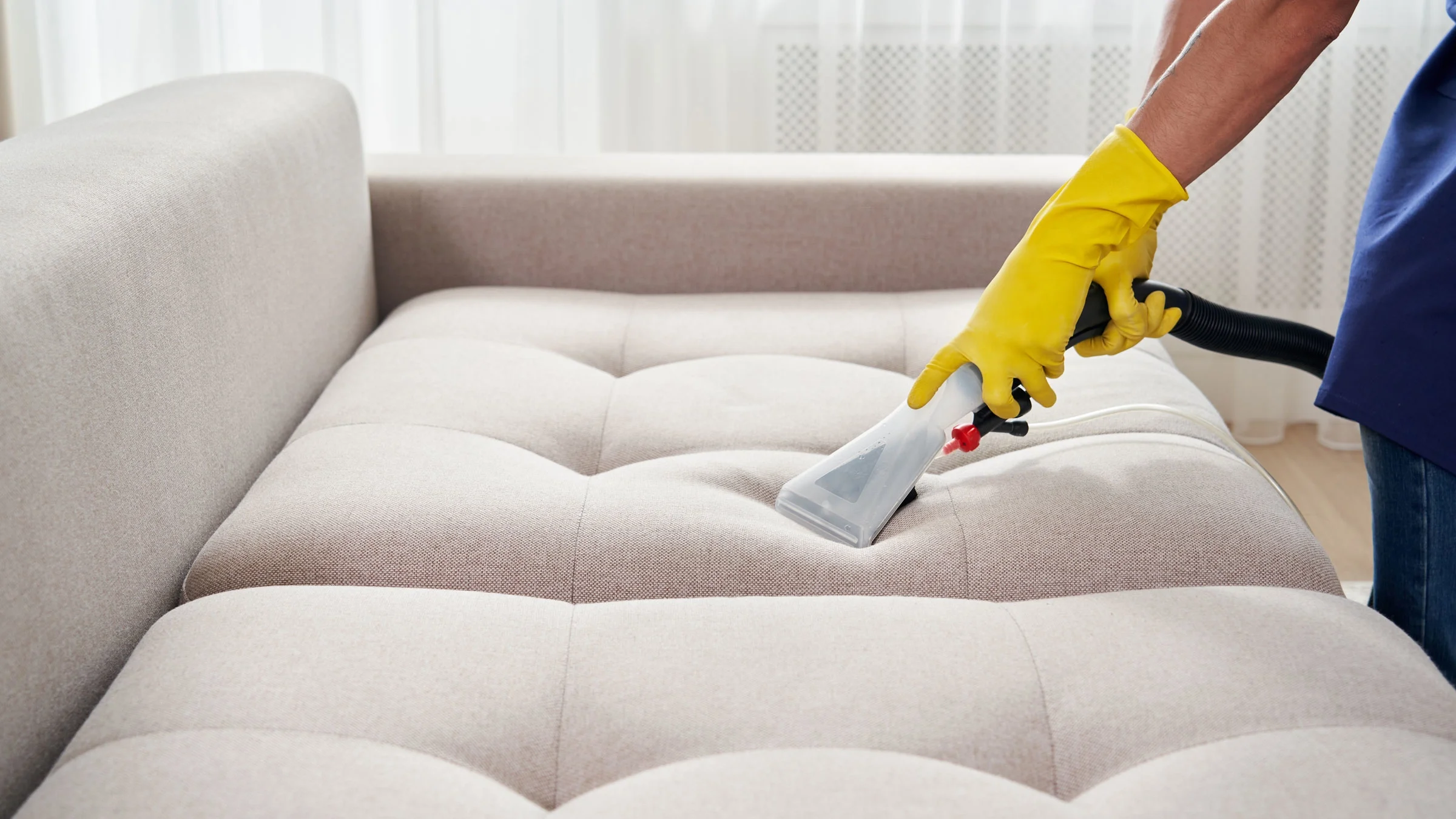 A sofa is getting steam cleaned in a close-up.