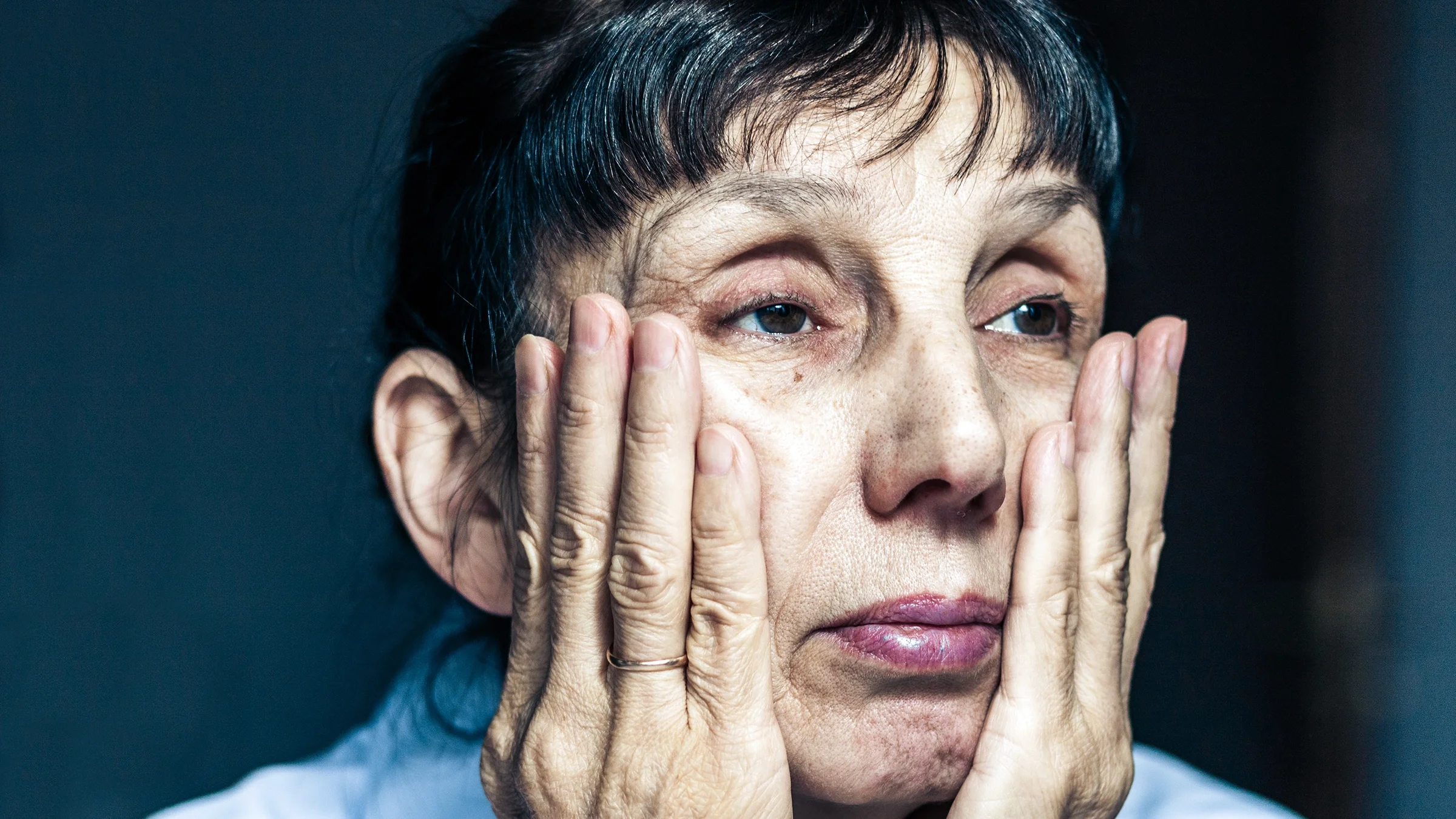 An older person placed their hands on their face.