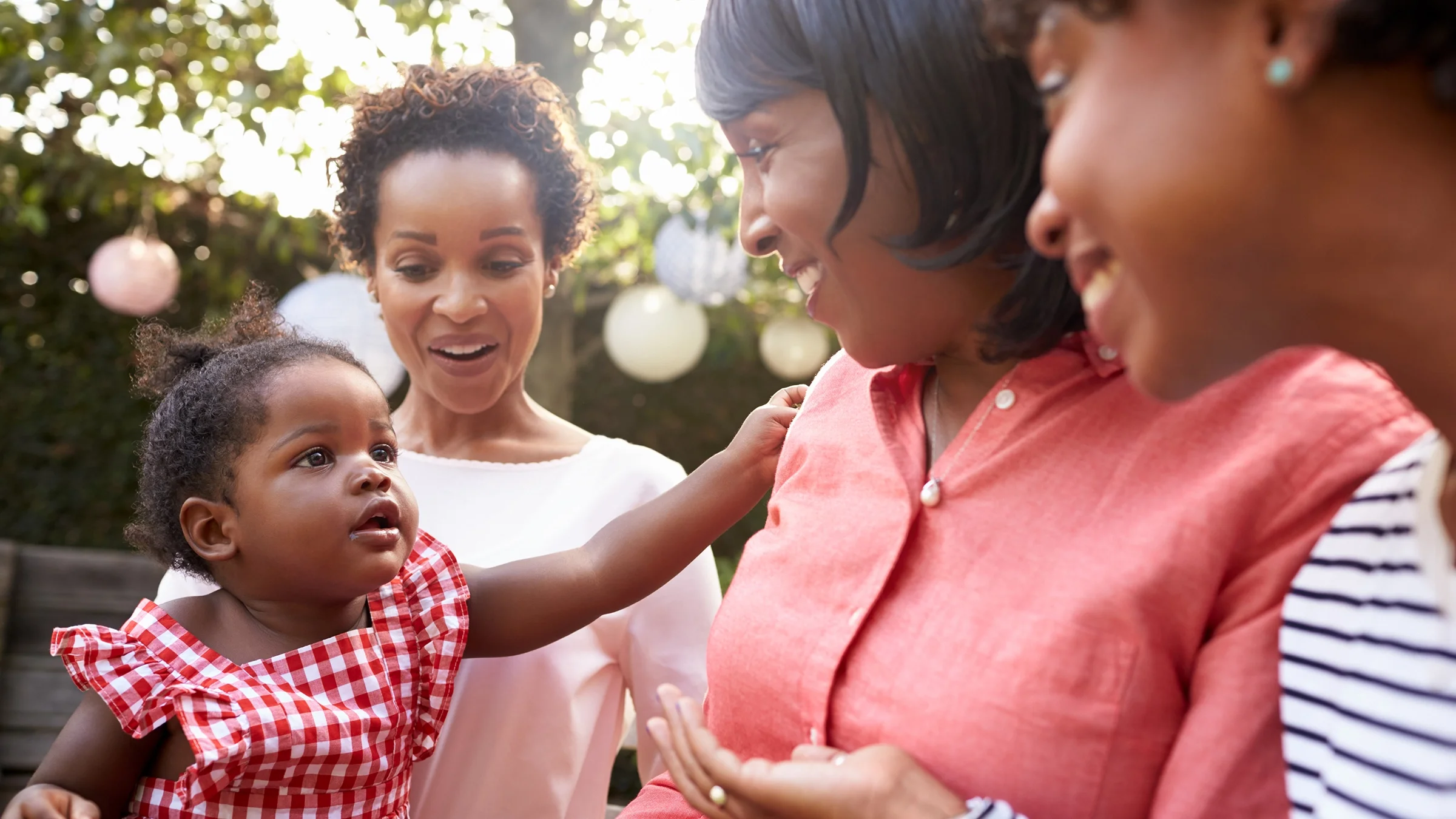 Multigenerational family portrait of a grandmother, daughters, and baby granddaughter outside.