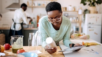 Supplements and herbs: woman reading tablet while in the kitchen 1399349475