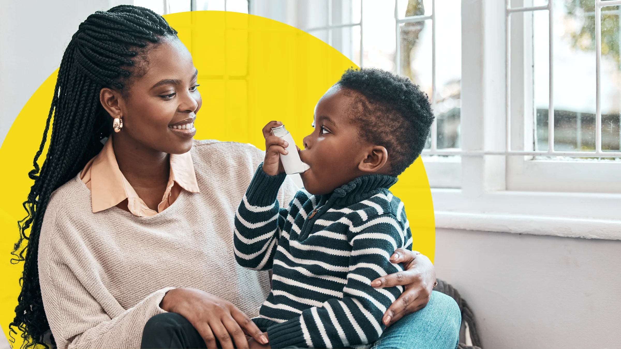 Young mother and son sitting together while the child uses his inhaler. There is an added yellow circle behind them.