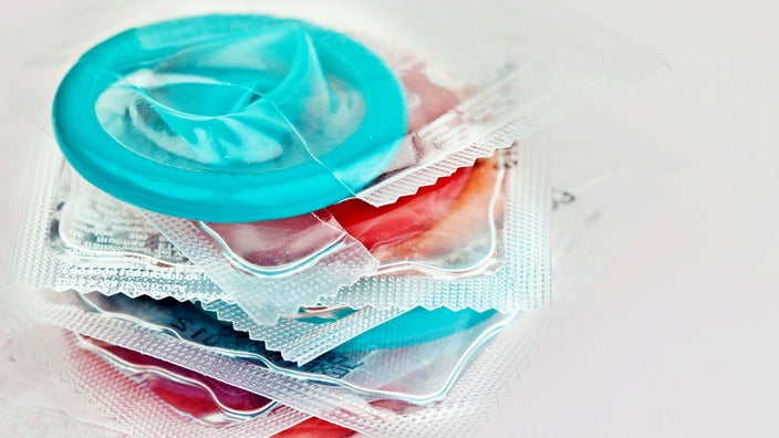 Stack of colorful condoms on a light gray background.