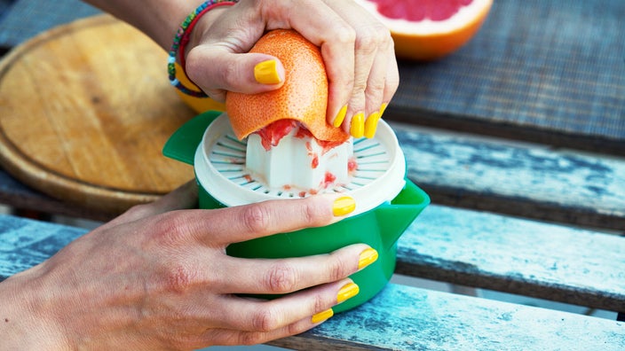 Cropped shot of hands squeezing grapefruit to make juice. 