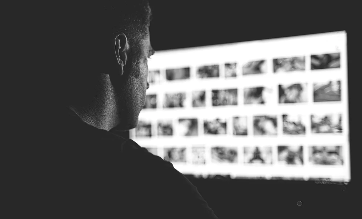 Black and white photo of a shadowed man looking at porn on the computer.