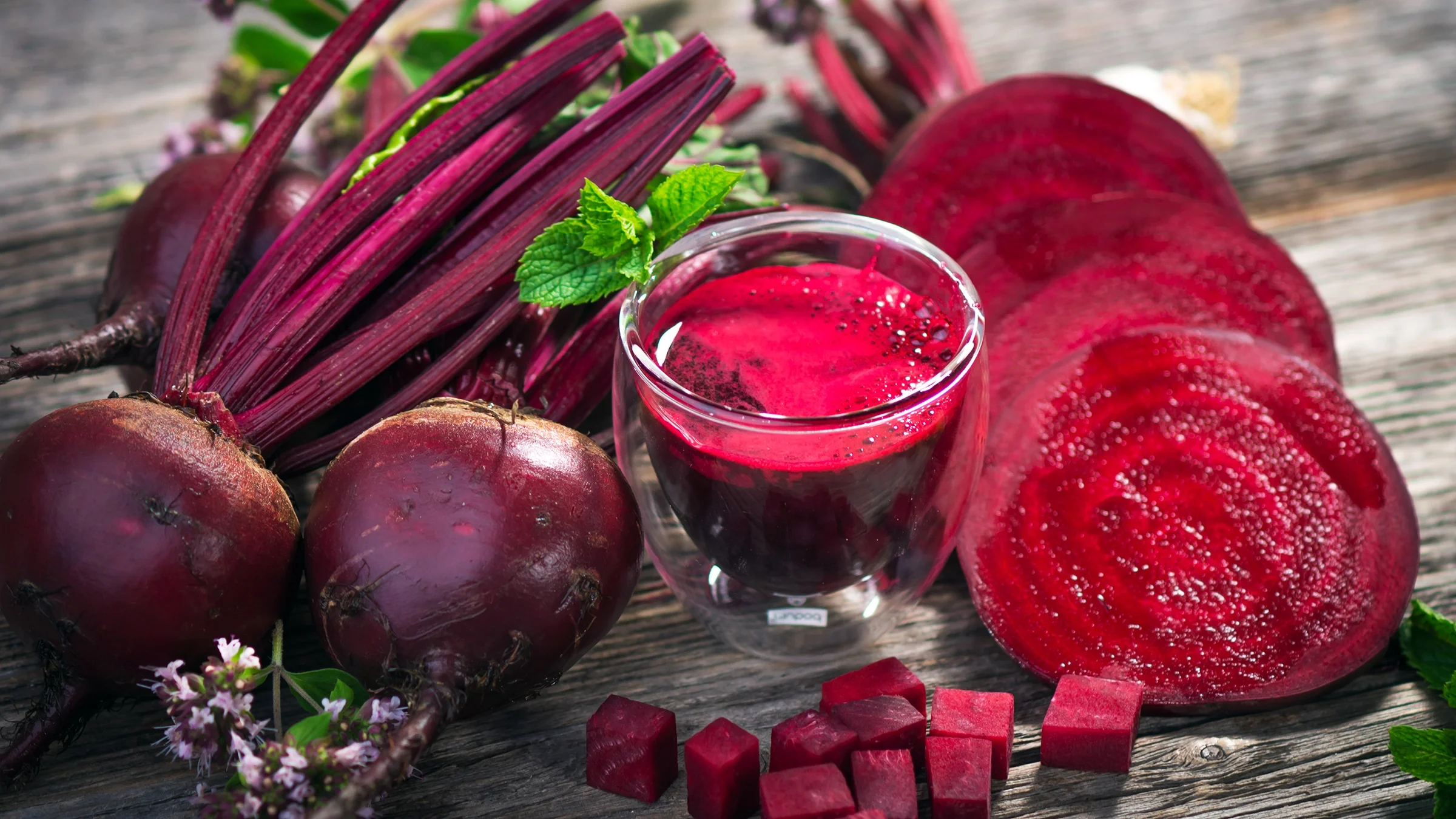 Beetroot juice and sliced beetroots on a wooden table