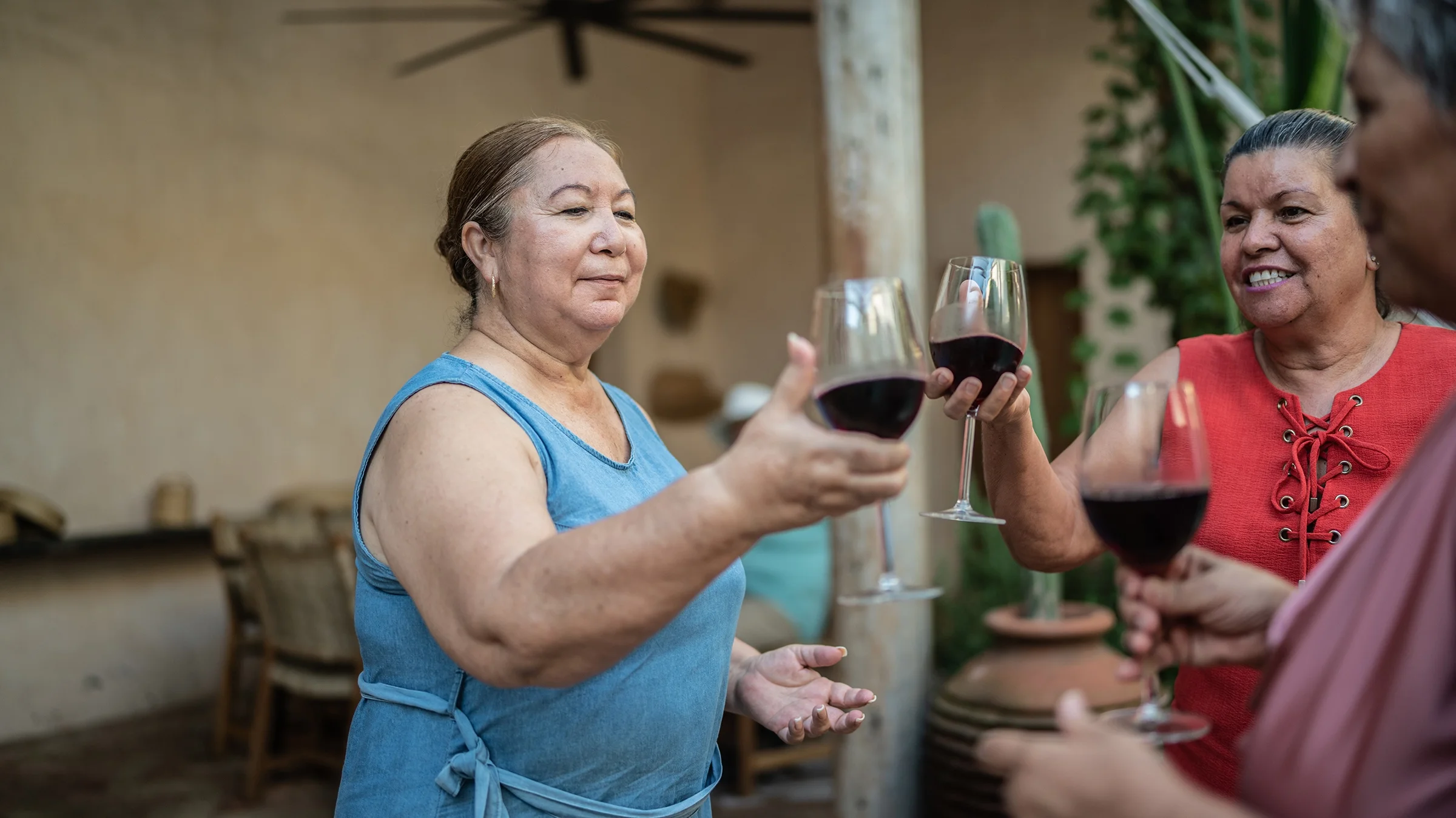 A group of friends toasts with glasses of red wine.