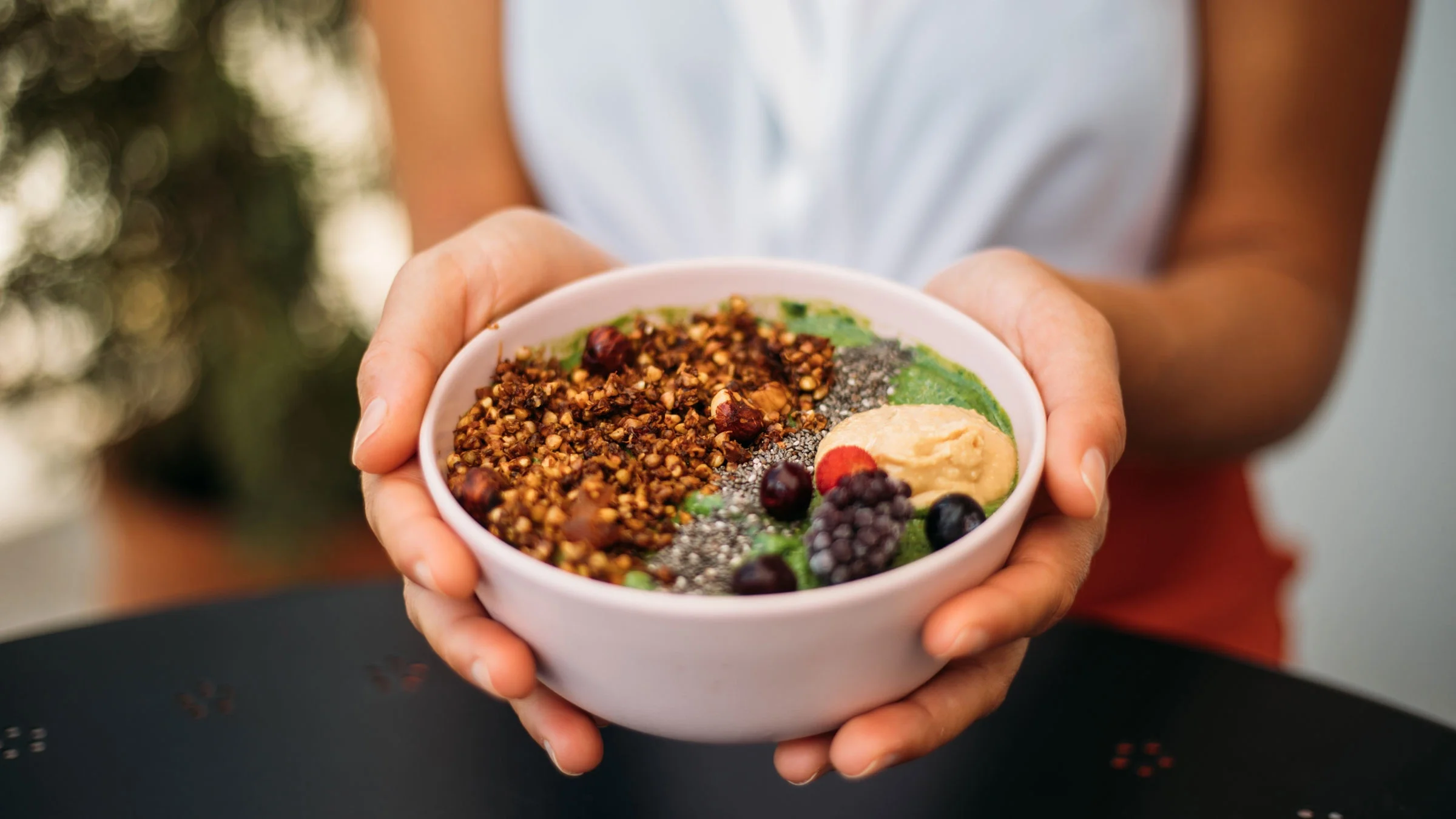 Hands holding bowl of antioxidant fruit and nuts