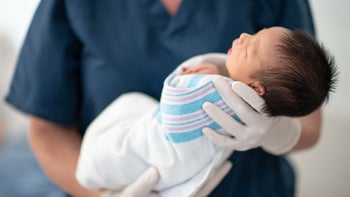 Health: Children's health: nurse holding baby in hospital blanket 1299693806