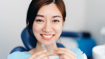Health: FSA HSA: closeup woman putting in clear retainer at dentist-1311280330
